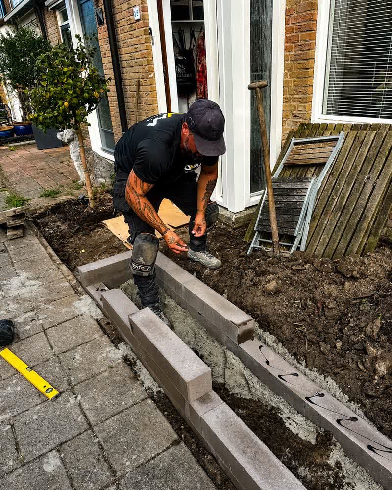 Stratenmaker plaatst opsluitbanden in de voortuin van een woning